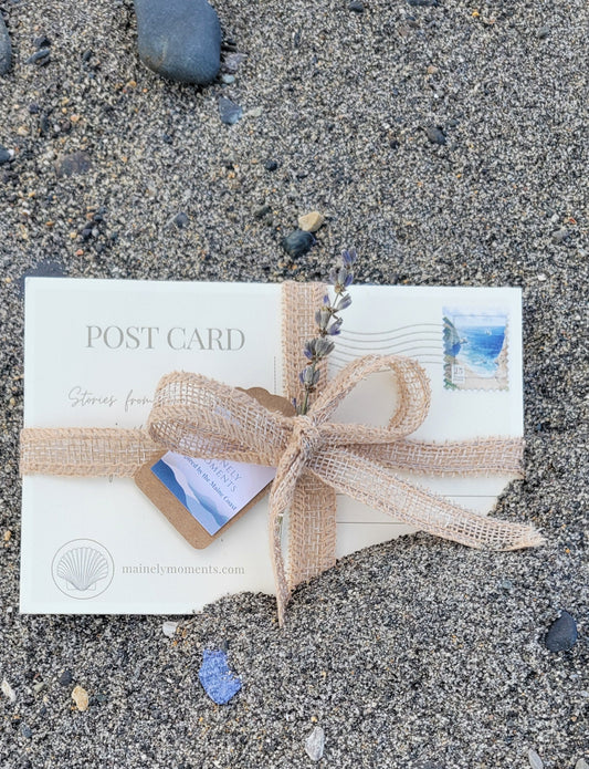 Postcard with a decorative bow on a sandy surface